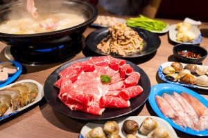 Hot pot with lots of food on the table